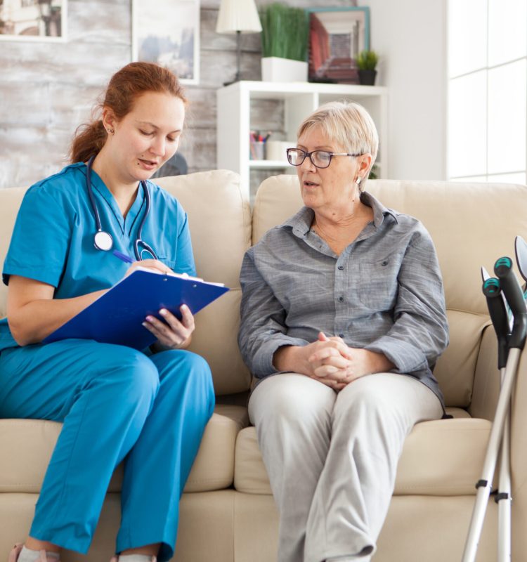 Female doctor in nursing home doing survey on senior woman with crutches